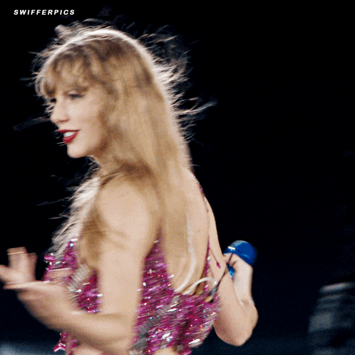 a woman in a pink dress is singing into a microphone and the words swifterpics are visible on the bottom