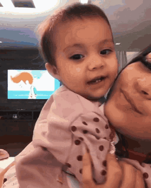 a baby is being held by a woman in front of a tv