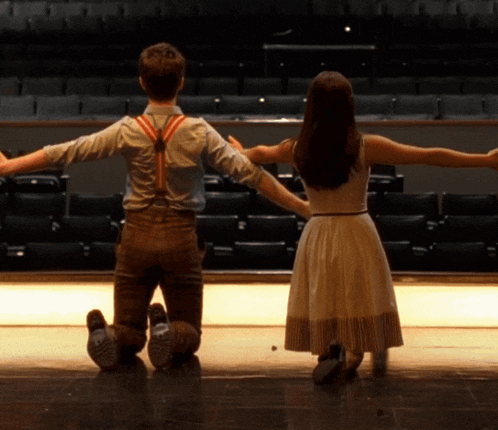 a boy and a girl are kneeling on the floor holding hands