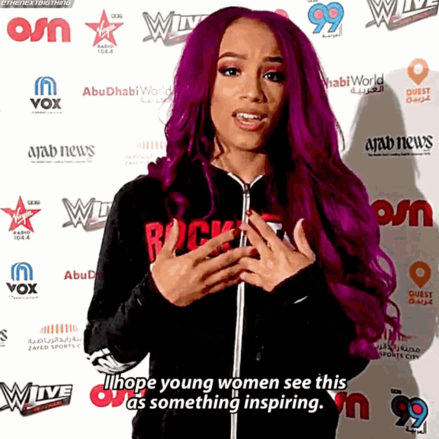 a woman with purple hair says i hope young women see this as something inspiring in front of a wall of logos