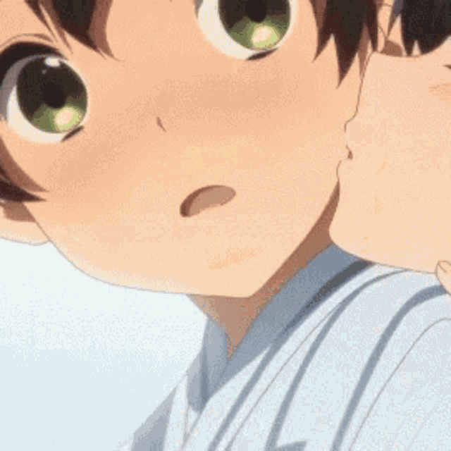 a close up of a person 's face with green eyes being kissed by another person .