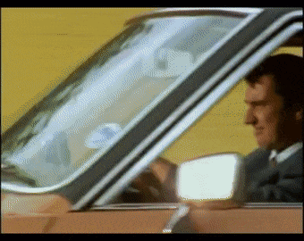 a man in a suit is driving a car with a sticker on the windshield that says ' toyota '