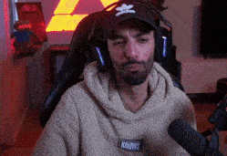 a man wearing headphones and a sweatshirt that says knows is sitting in front of a microphone