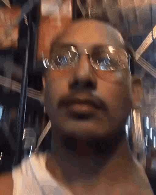 a man with a mustache wearing sunglasses and a tank top