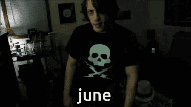 a man wearing a black shirt with a skull and lightning bolt and the word june on it