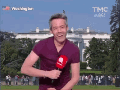 a man is holding a microphone in front of a white house .