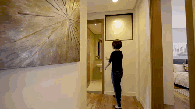 a woman stands in a hallway with a picture on the wall