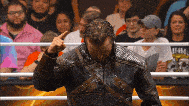 a man in a leather jacket is standing in front of a crowd and giving the middle finger