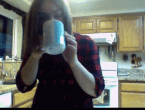 a woman in a plaid shirt is drinking from a cup