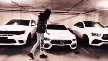 a man is standing in front of a row of white cars in a garage .