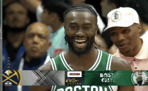 a man in a boston celtics jersey smiles in front of a group of people
