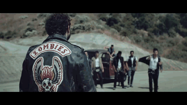 a man wearing a leather jacket that says zombies on it