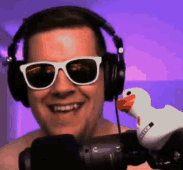 a man wearing sunglasses and headphones holds a stuffed duck