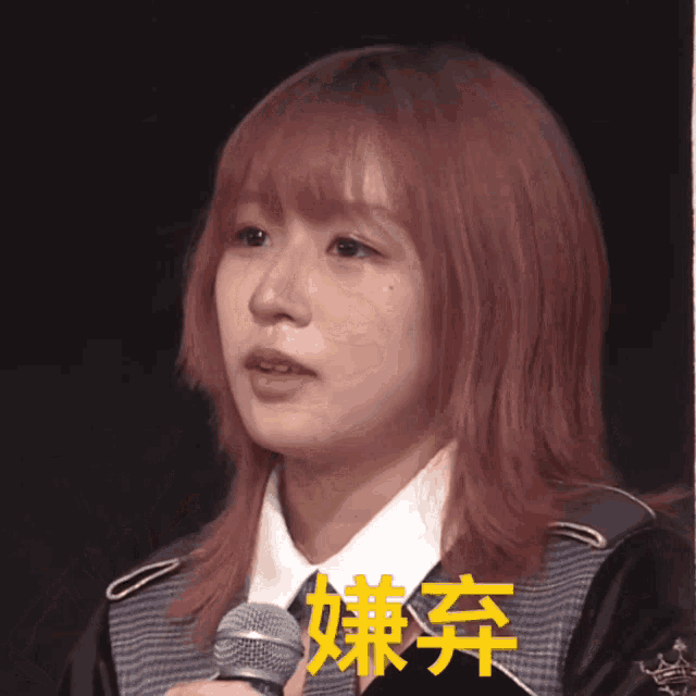 a girl with red hair is holding a microphone in front of a sign that says ' a ' on it
