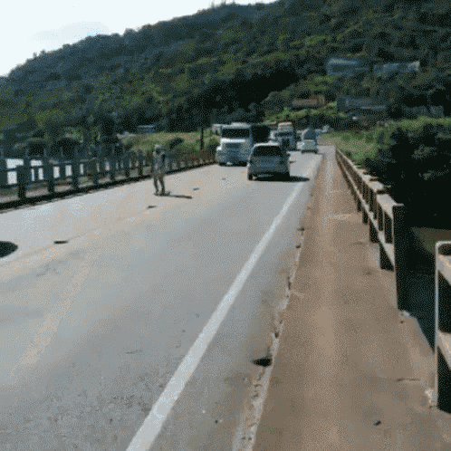 a couple of people walking across a bridge over a highway
