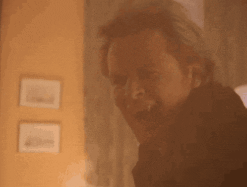 a close up of a man with vampire teeth making a funny face in a room .