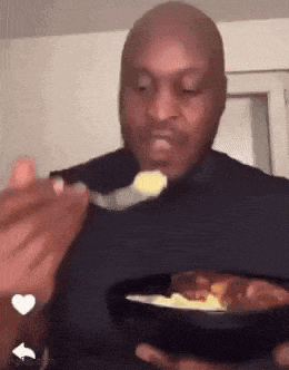 a bald man is eating food with a spoon from a plate .