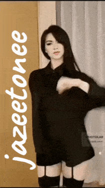 a woman in a black shirt is standing in front of a window with the name jazeetonee on the bottom