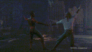 a man with horns is standing next to a woman with a ponytail in a dark room .