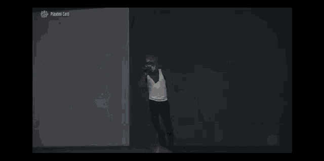 a man in a white tank top is running with a microphone in front of a screen that says pound coins on it