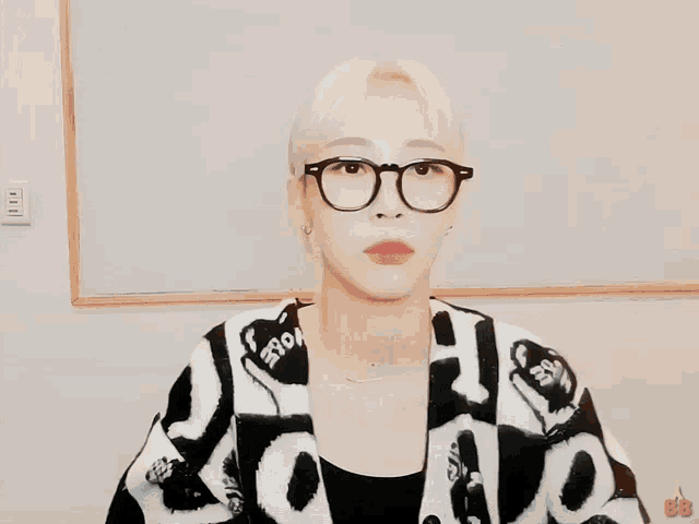 a woman wearing glasses and a black and white sweater with the word bb on the bottom