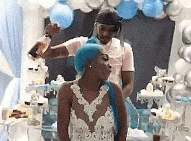 a man is pouring a drink into a woman 's hair at a baby shower .