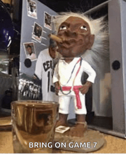 a statue of a man smoking a cigar next to a shot glass that says bring on game 7 on it