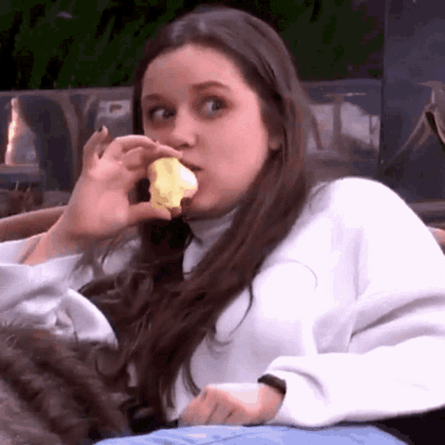 a woman with long hair is eating a cupcake