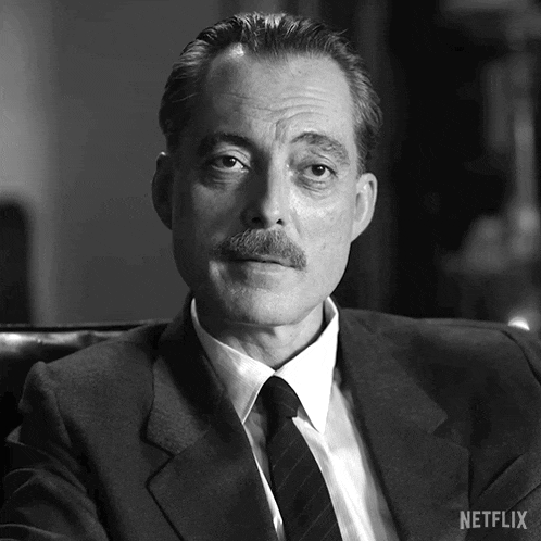 a man in a suit and tie is sitting in a chair with a netflix logo on the bottom right