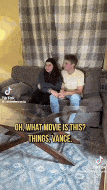 a man and a woman are sitting on a couch with a glass coffee table .