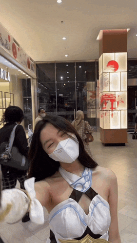 a woman wearing a white mask is standing in front of a sign that says ' rla ' on it