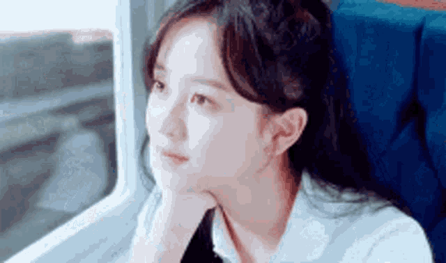 a young woman is sitting in a train seat looking out the window .