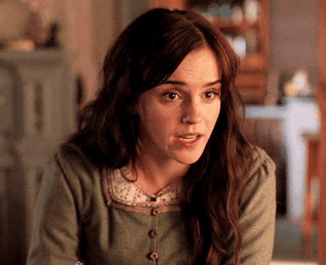 a woman with long brown hair is wearing a green sweater with buttons