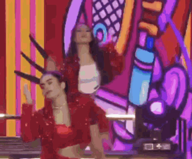 two women are dancing on a stage in front of a colorful mural .