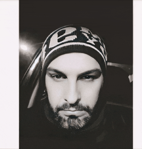 a black and white photo of a man wearing a beanie that says ea on it