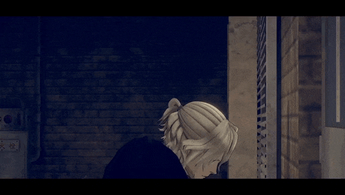 a man with blonde hair is standing in a dark room with a brick wall