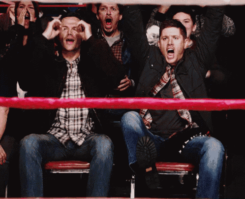 a man in a plaid shirt is sitting in a boxing ring with his mouth open
