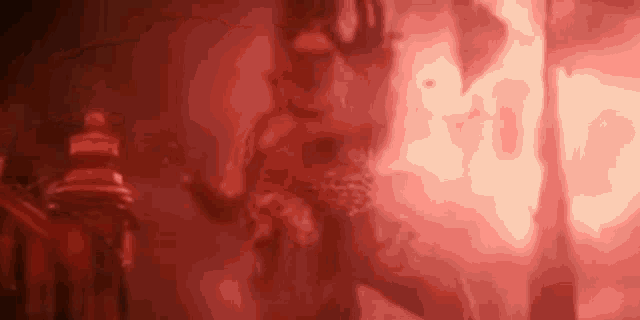 a person is standing in a dark room with red smoke coming out of it .