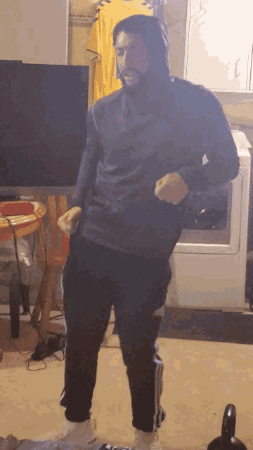 a man in a hoodie is dancing in front of a washing machine
