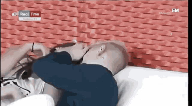a man with a tattoo on his head is laying on a bed with a woman .