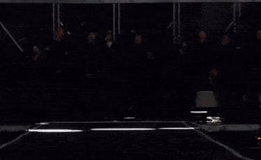 a man in a black jacket is standing in front of a crowd of people dancing