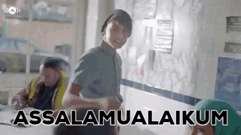 a man is standing in a room with the words assalamualaikum written on the wall .