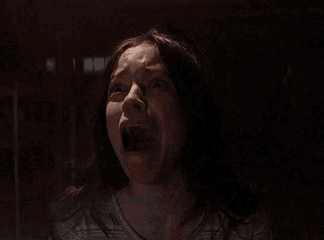 a girl is covering her mouth with her hand in a dark room .