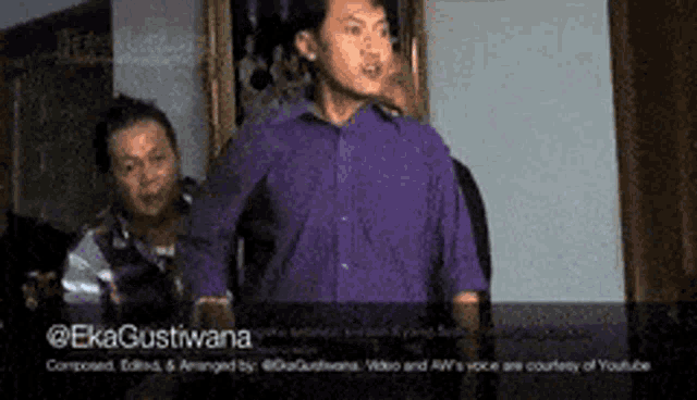 a man in a purple shirt is standing in front of a painting .