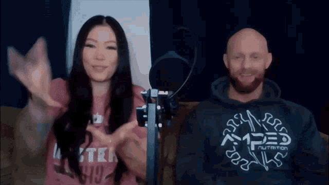a man and a woman are sitting in front of a microphone and the man is wearing a hoodie that says apex nutrition