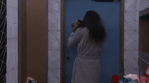 a woman in a robe is standing in front of a door .