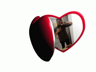 a heart shaped mirror with a man taking a selfie in it