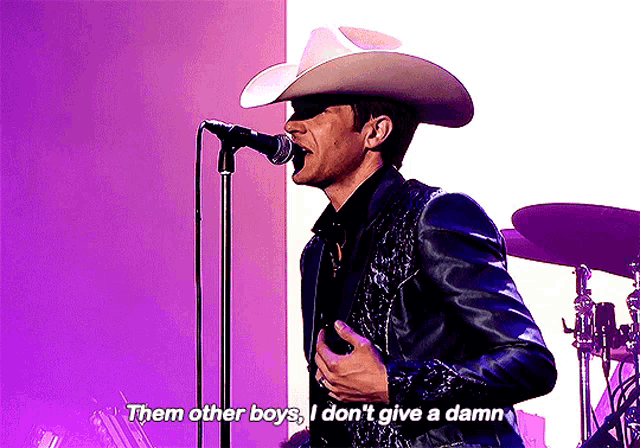 a man singing into a microphone with the words " them other boys i don 't give a damn " written below