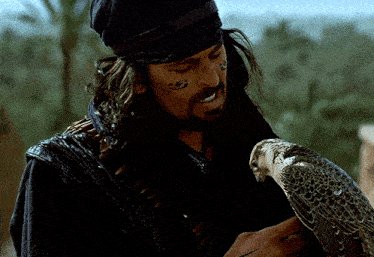 a man with a tattoo on his face holds a bird in his hand