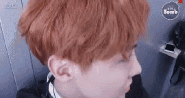 a close up of a person 's face with red hair and a black shirt .